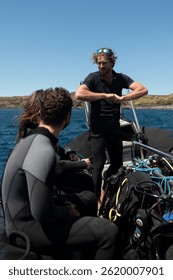 Diving instructor giving safety instructions to scuba divers on a boat before diving into the ocean