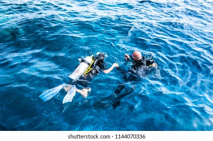 diving instructor holding a disciple's hand in blue water
