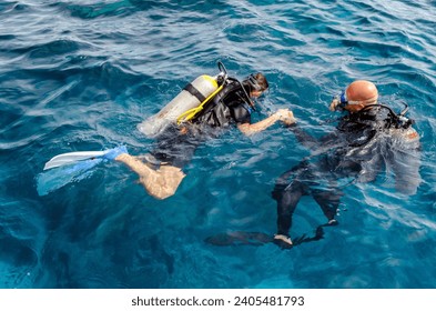 diving instructor holding a disciple's hand in blue water in Egypt Red Sea