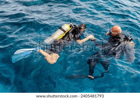 diving instructor holding a disciple's hand in blue water in Egypt Red Sea