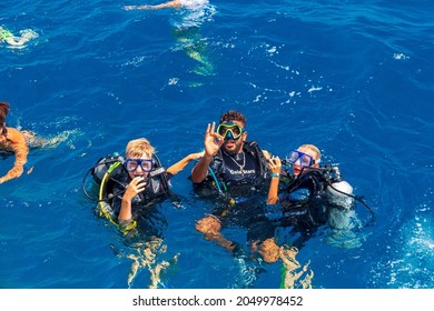 Diving Instructor Teaches Children To Scuba Dive Underwater. Discover Scuba Diving, Kids. Happy Family - Father, Son And Daughter In A Mask. Red Sea Egypt August 30, 2021