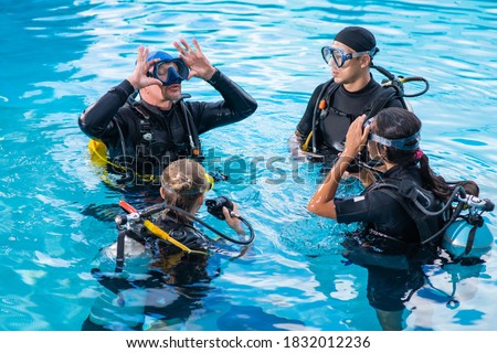 Diving instructor teaches how to attach the mask for students