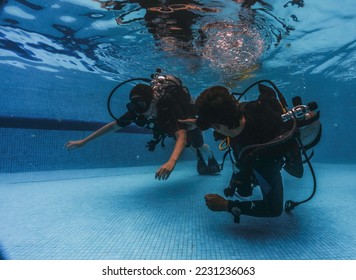 diving instructor teaches students to scuba dive in swimming pool. couple getting first experience with scuba diving under the guidance of experienced recreational diving instructor on vacation. - Powered by Shutterstock