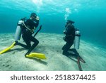 Diving instructor trains a novice who is learning to dive , underwater , Red sea .