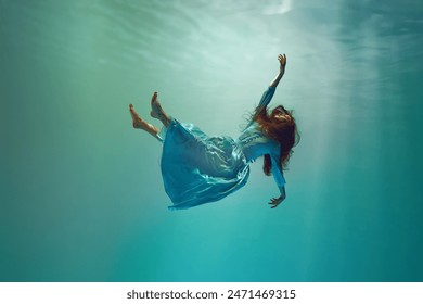 Diving into unknown. Surreal underwater scene featuring elegant young woman levitating gracefully underwater. Concept of surrealism, beauty, mystery and fantasy, freedom - Powered by Shutterstock