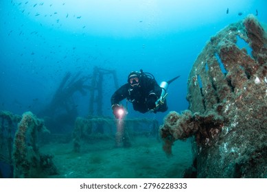 Diving team conducts technical deep dives at a shipwreck site in Croatia, examining the underwater structures and marine environment. Divers use flashlights to explore.