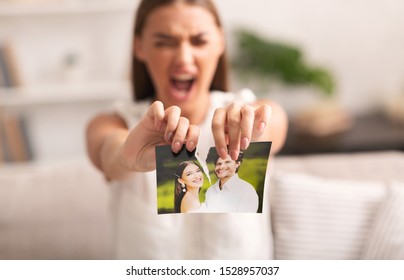 Divorce. Angry Woman Ripping Wedding Photo With Ex-Husband After Breakup Indoor. Selective Focus