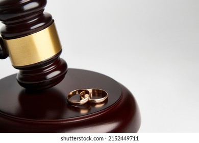 Divorce Concept, Canceling Marriage, Legal Separation. Wedding Rings And Judge Gavel On White Background With Copy Space, Close-up