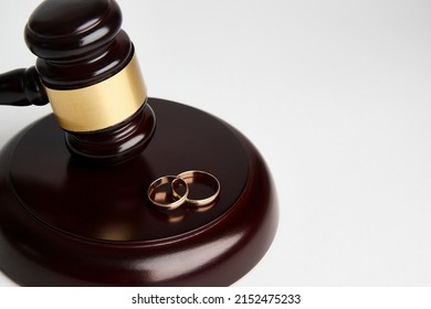 Divorce Concept, Canceling Marriage, Legal Separation. Wedding Rings And Judge Gavel On White Background With Copy Space, Close-up