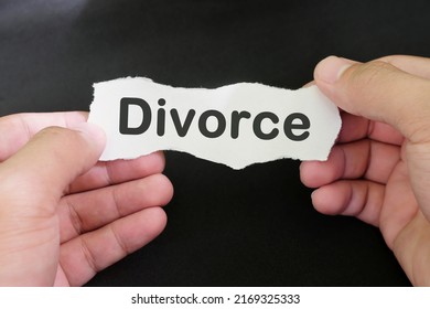 Divorce concept. Hand holding a piece of paper with written divorce on black background