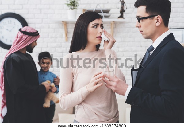 Divorce lawyer in suit in office with\
arab husband and wife. Man is getting custody of his\
son.
