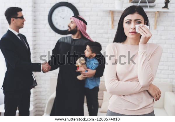Divorce lawyer in suit in office with\
arab husband and wife. Man is getting custody of his\
son.
