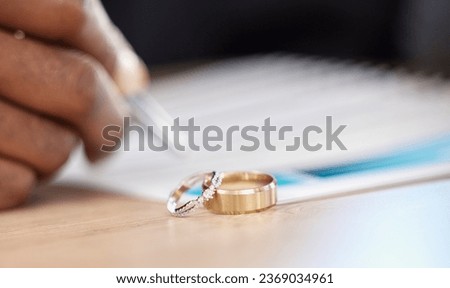 Divorce, rings and signature on paperwork for a lawyer, register wedding or writing on a contract. Table, closeup and a certificate, planning or legal documrnts for a commitment or engagement