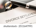 Divorce settlement agreement paperwork displayed alongside a wedding ring and a fountain pen, representing legal processes in family law and the dissolution of marriage.