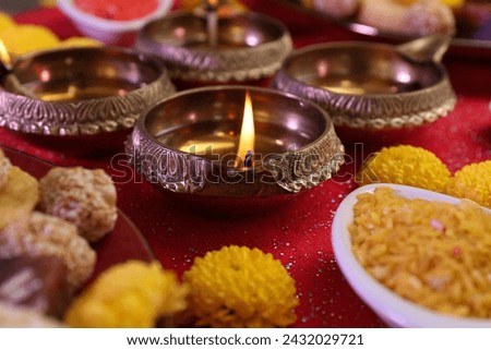 Diwali celebration. Beautiful composition with diya lamps, tasty Indian sweets and bright rangoli on shiny red table, closeup