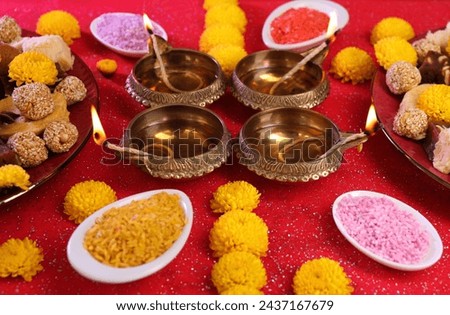 Diwali celebration. Beautiful composition with diya lamps, tasty Indian sweets and bright rangoli on shiny red table