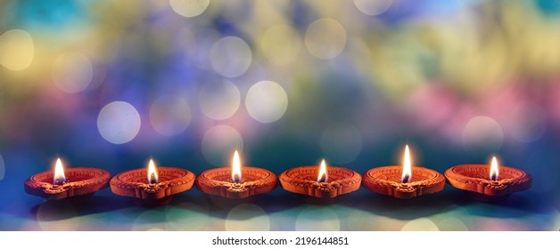 Diwali celebration. Deepavali Hindu festival of lights. Clay diyas candles in a row. Oil lamps lit on bokeh blue background
