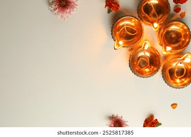 Diwali celebration. Diya lamps and beautiful flowers on light textured surface, flat lay. Space for text - Powered by Shutterstock