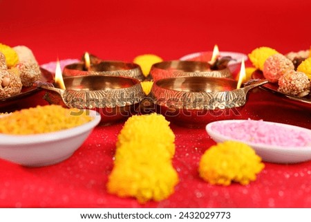 Diwali celebration. Diya lamps and bright rangoli on shiny red table, closeup