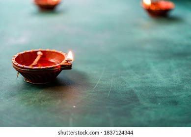 Diwali And Deepavali Background With Clay Or Earthen Lamps Or Diyas On A Green Concrete Surface With Mithai Like Kaju Katli Or Sweets And Traditional Flowers Like Palash For Pooja Or Poja Offering 