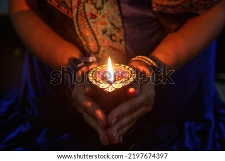 Diwali, Deepavali Hindu Festival of lights celebration. Diya oil lamp lit in woman hands, dark background. close up view. 
