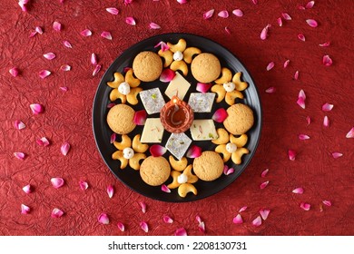 Diwali Diya On Red Background, Sweets OR Mithai In Indian Thali  Arranged Over Decorative Background. Selective Focus, Indian Festival