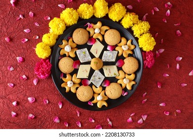 Diwali Diya On Red Background, Sweets OR Mithai In Indian Thali  Arranged Over Decorative Background. Selective Focus, Indian Festival