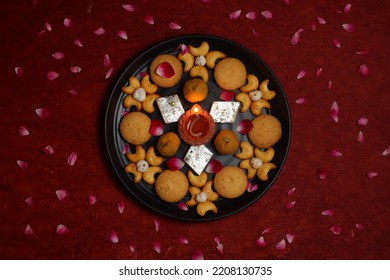 Diwali Diya On Red Background, Sweets OR Mithai In Indian Thali  Arranged Over Decorative Background. Selective Focus, Indian Festival