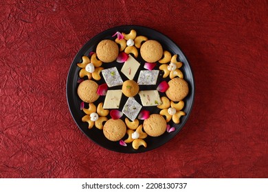 Diwali Diya On Red Background, Sweets OR Mithai In Indian Thali  Arranged Over Decorative Background. Selective Focus, Indian Festival