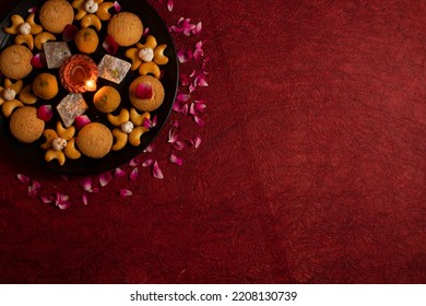 Diwali Diya On Red Background, Sweets OR Mithai In Indian Thali  Arranged Over Decorative Background. Selective Focus, Indian Festival