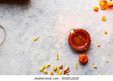 Diwali Diyas And Sweet Or Mithai On A White Rustic Wall Background With Flowers And Earthen Lamps