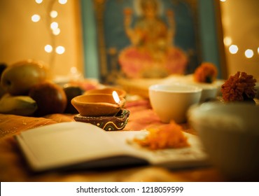 Diwali Puja Set Up. Selective Focus On Burning Traditional Earthen Lamp Surrounded By An Elaborate Laxmi Puja. 