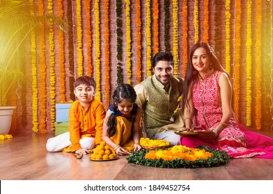 Diwali Or Rakshabandhan Celebration - Indian Young Family Of Four Celebrating Deepavali Or Bhai Dooj Festival With Sweet Laddoo, Oil Lamp Or Diya And Gift Boxes, Eating Food Or Taking Selfie