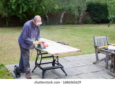 DIY Carpentry And Home Improvement, Man Using A Circular Saw To Resize A Wooden Door, UK