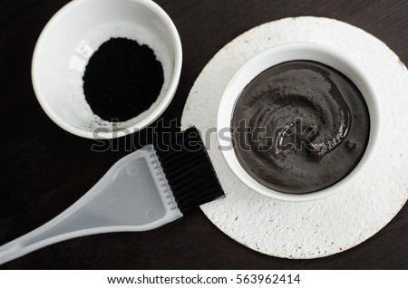 DIY charcoal face mask in a small ceramic bowl. Homemade cosmetics. 