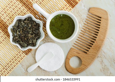 Diy Green Tea Matcha Mask (scrub) The Small White Bowl, Dry Green Tea Leaves, Cotton Pad And Wooden Hair Brush. Homemade Natural Beauty Treatment, Face Or Hair Mask, Spa Recipe. Top View, Copy Space.
