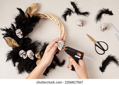 DIY Halloween Wreath Background. Process Of Making Wreath With Glue Gun, Black Feathers, Skulls And Golden Leaves