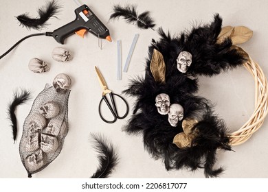 DIY Halloween Wreath Background. Process Of Making Wreath With Glue Gun, Black Feathers, Skulls And Golden Leaves