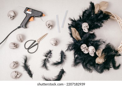 DIY Halloween Wreath Background. Process Of Making Wreath With Glue Gun, Black Feathers, Skulls And Golden Leaves