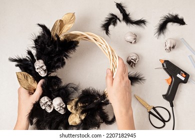 DIY Halloween Wreath Background. Process Of Making Wreath With Glue Gun, Black Feathers, Skulls And Golden Leaves