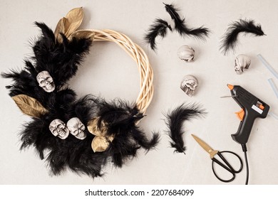 DIY Halloween Wreath Background. Process Of Making Wreath With Glue Gun, Black Feathers, Skulls And Golden Leaves