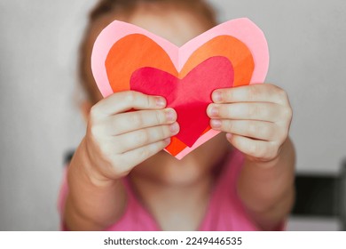 DIY holiday card with a red paper heart, a symbol of love. child holding homemade paper cut hearts Mother's Day, Valentine's Day - Powered by Shutterstock