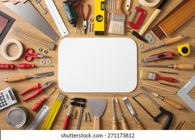 DIY And Home Improvement Banner With Work And Construction Tools On A Wooden Workbench Top View, Blank White Sign At Center