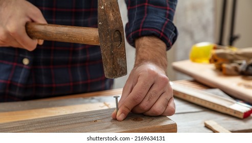 DIY, Home Repair And Fix. Carpenter Nail Wood. Male Hand Hold Hammer And Nail, Work Bench Table Background.
