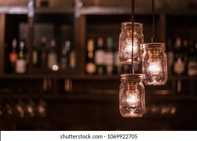 DIY light bulb cover, hanging lamps made from glass jars with wine shelf bar blurry background - Powered by Shutterstock