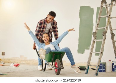 DIY, Painting And Happy Couple Smile While Moving Into New Home, Real Estate Property House Or Building. Love, Creative Man And Woman On Wheelbarrow Interior Design And Renovation Work On Room Wall