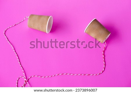 DIY paper cups with string on pink background. Concept, telephone toy. Concept, telephone toys which apply with science knowledge about vibration sound through straining strings causing us to hear.   