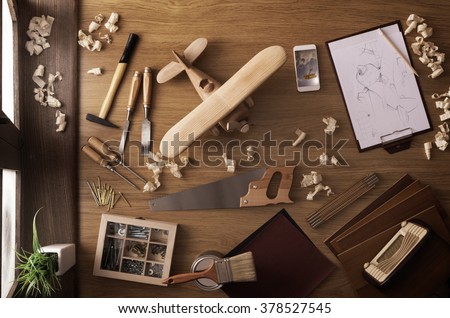 DIY project at home concept, work table with handmade wooden toy airplane and carpentry work tools, top view