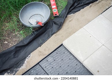 DIY Sidewalk Project With Trowel, Level, Weed Barrier And Leveling Paver Sand To Hold The Concrete Patio Stone On Paver Base Panel With Edging. Pathway Walkway Outdoor Landscaping In Texas, USA