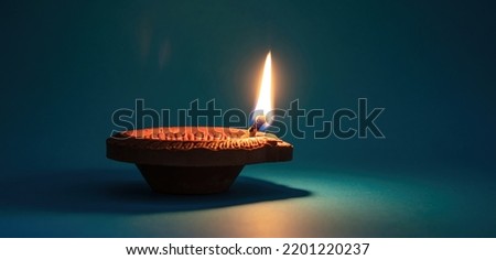 Diya oil lamp lit. Diwali, Deepavali Hindu Festival of lights celebration, blue background. Indian holiday template

